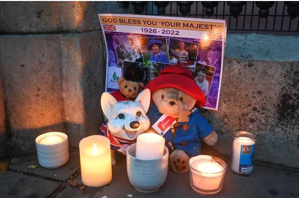 Mourners place a Paddington Bear plush next to a corgi figurine as an ode to Queen Elizabeth II outside Buckingham Palace