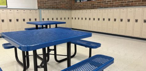 Senior locker bay, 2 blue tables visible with a ring of yellow lockers in the background. A yellow, tiled floor is also visible.