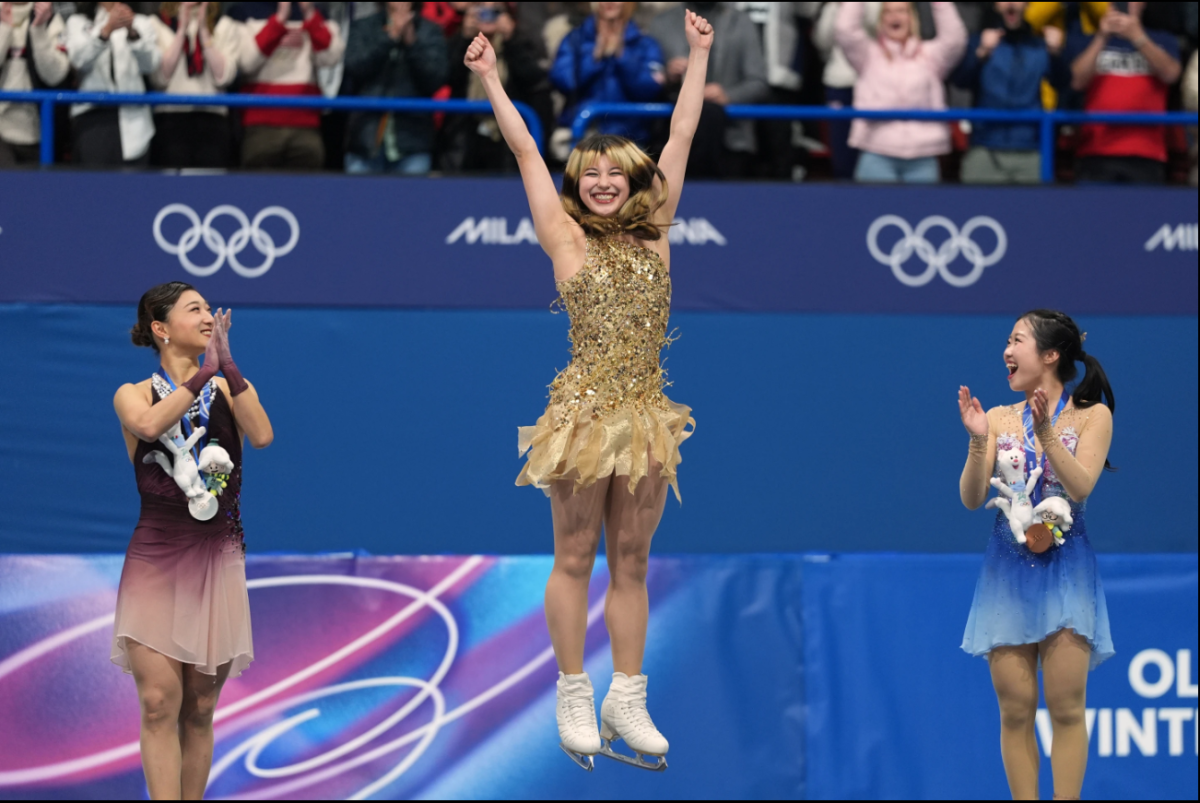Alysa Liu accepts her gold medal in the women's free skate to applause from Japanese figure skaters Kaori Sakamoto and Ami Nakai.